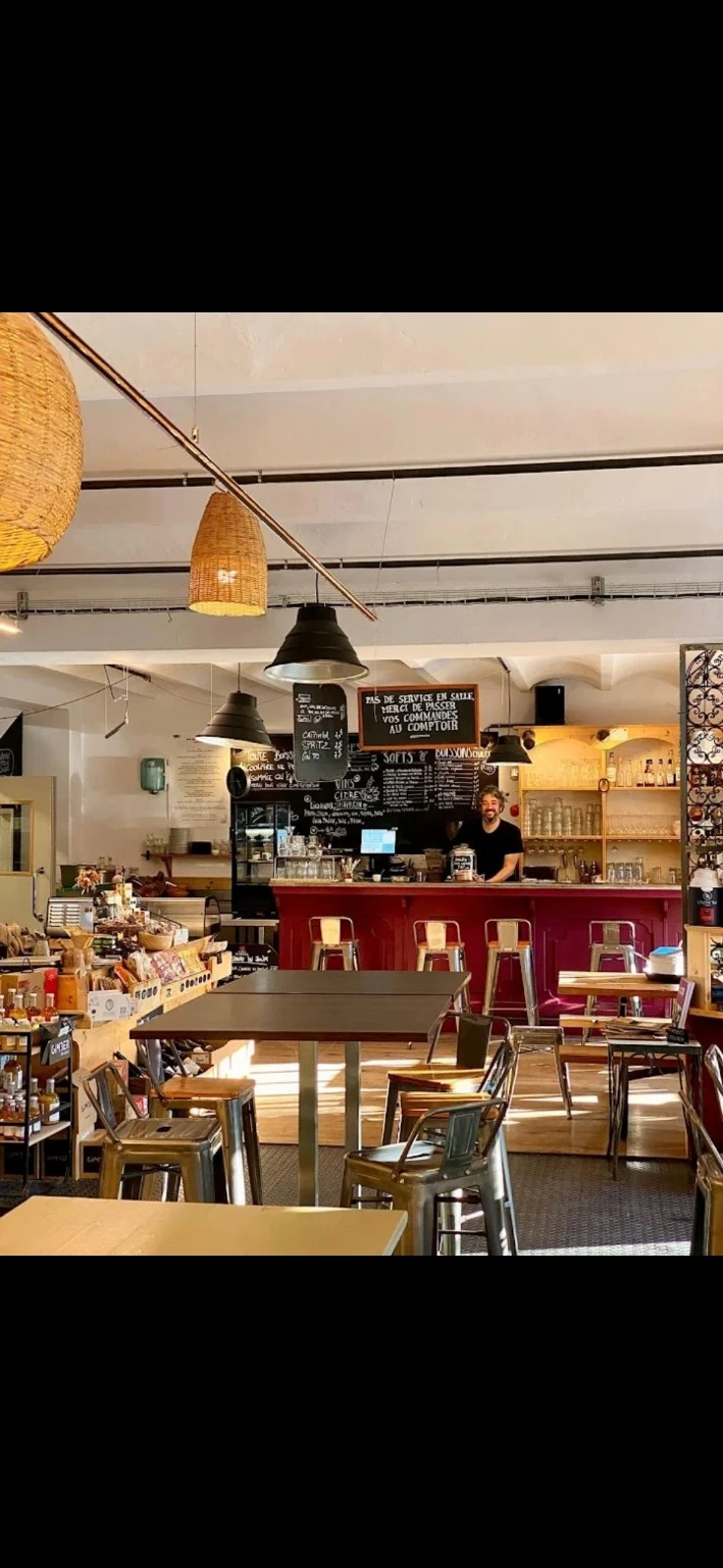 Le chef de COMBO souriant, wok en main, devant le comptoir de l'épicerie